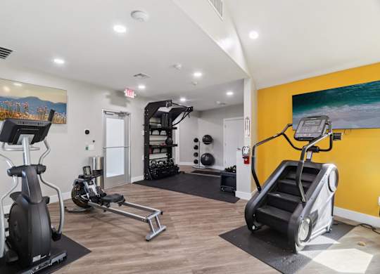 A gym with a yellow wall and a painting of a mountain scene.