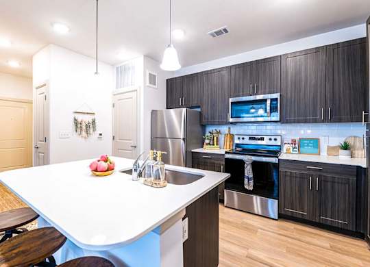 A modern kitchen with a white island and dark wood cabinets.