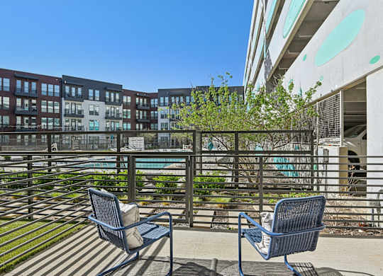 Two chairs are on a patio with a pool in the background.