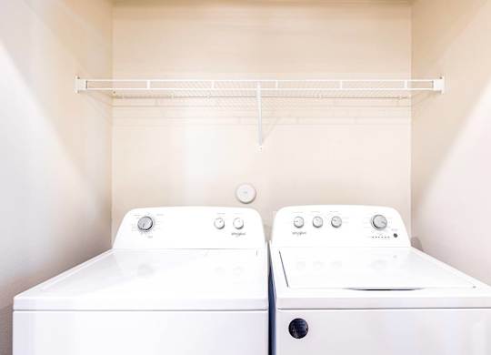 Two white washing machines in a small laundry room.