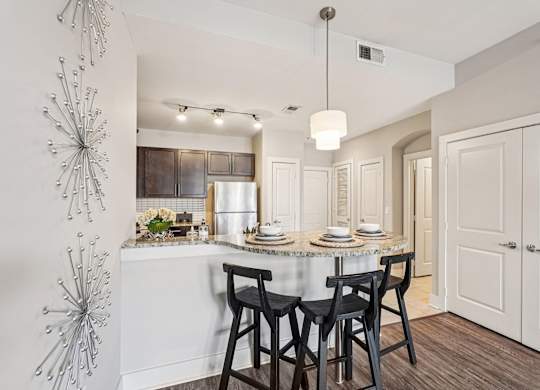 A modern kitchen with a dining table set for two.