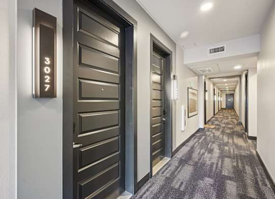 A hallway with doors numbered 3027.