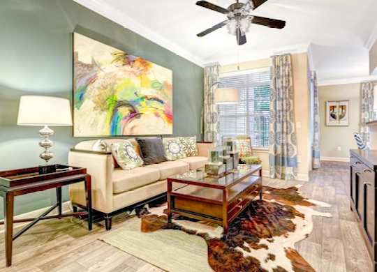 A living room with a couch, a coffee table, and a painting on the wall.