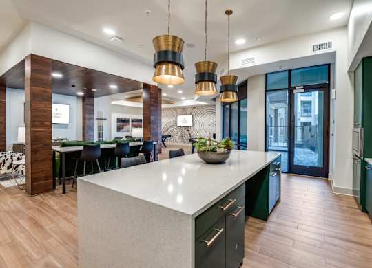A modern kitchen with a large island and pendant lights.