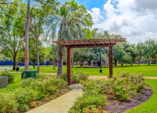 A park with a wooden pergola and a pathway.
