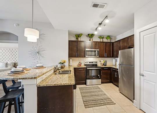 A kitchen with a refrigerator, sink, and oven.
