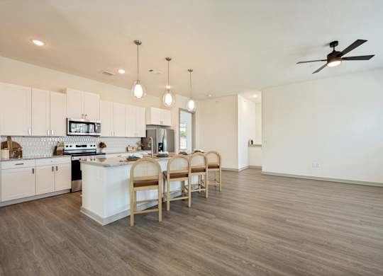 A kitchen with a white counter and wooden chairs.