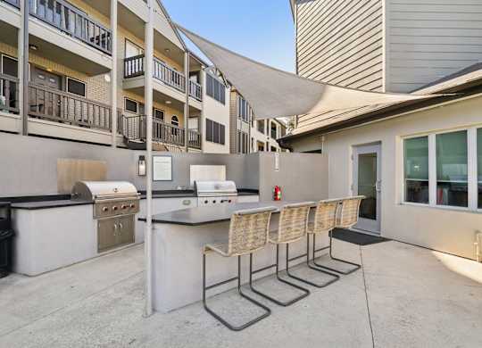 A patio with a barbecue grill and chairs.