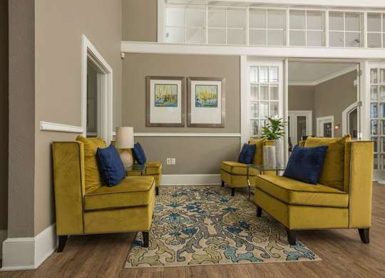 a living room with yellow couches and a blue rug