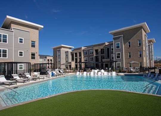 A large swimming pool in front of apartment buildings.