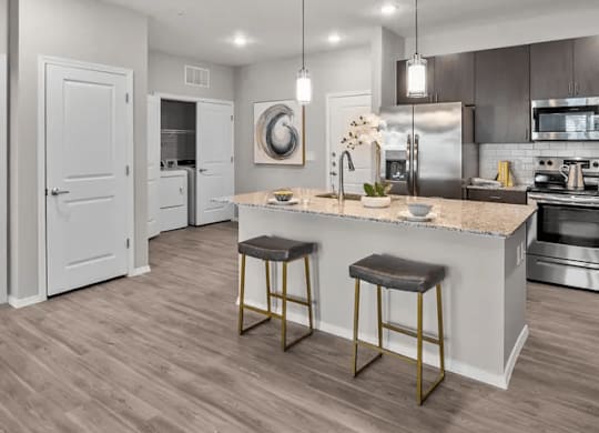 A modern kitchen with a white island and bar stools.