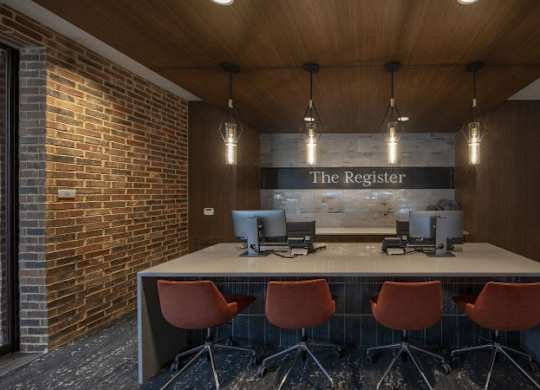 A conference room with a long table and chairs, a computer, and a sign that reads "The Register.".