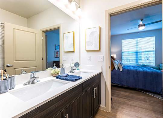 A bathroom with a blue bedroom in the background.
