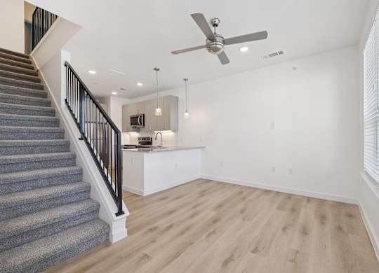 A spacious room with a staircase and a ceiling fan.