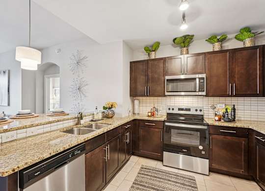 A modern kitchen with brown cabinets and stainless steel appliances.