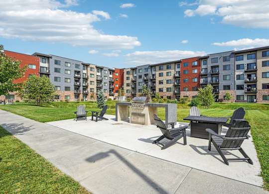A sunny day at a park with a concrete table and chairs and apartment buildings in the background.
