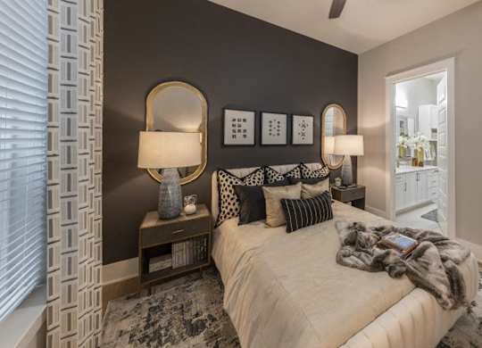 A bedroom with a bed, two lamps, and a mirror on the wall.