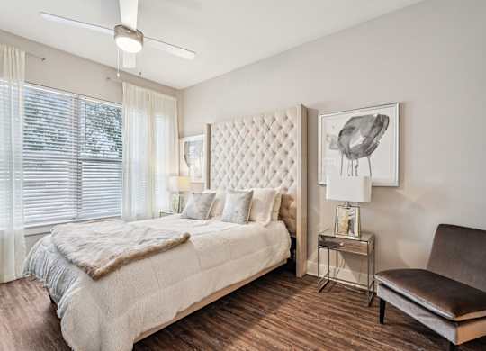 A bedroom with a large bed and a chair.