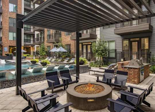 A patio with a fire pit and chairs.