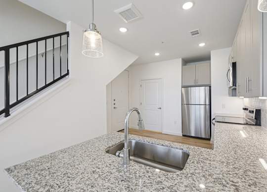 A kitchen with a granite countertop and a stainless steel sink.