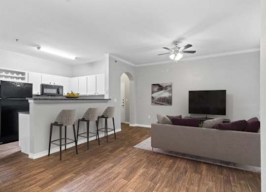 a living room with a couch and a kitchen with a bar and a tv