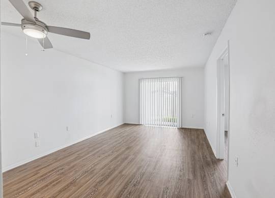 A room with a ceiling fan and wooden flooring.