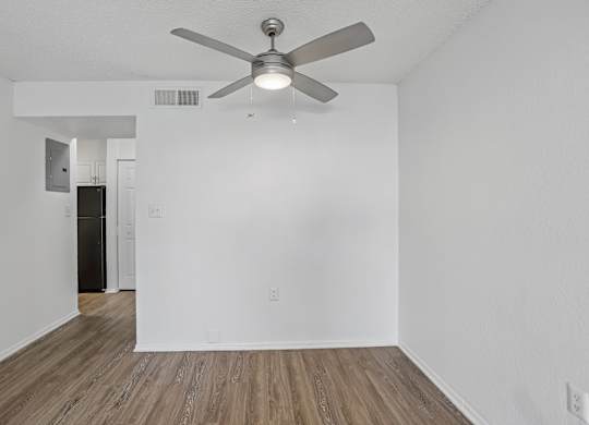 A room with a ceiling fan and wooden flooring.
