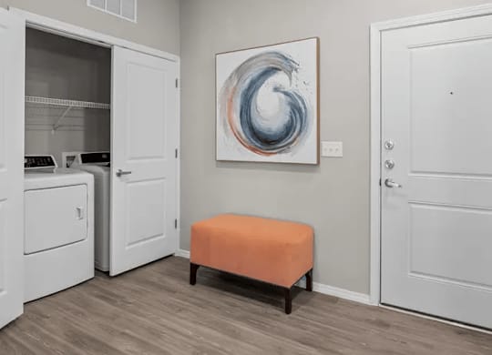 A room with a white door, a white cabinet, a white washing machine, a white fridge, a white wall, a white light switch, a white light, a white floor, a white ceiling, a white painting, a white