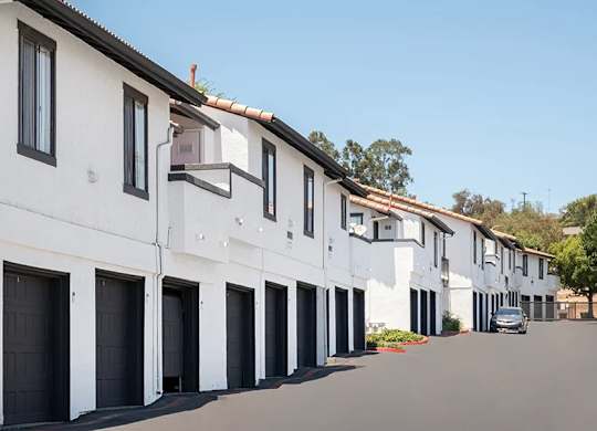 A row of white houses with black garage doors.