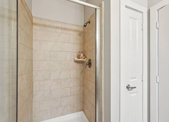A white door is open to a bathroom with a tiled shower.