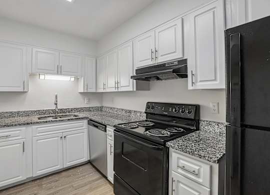 A kitchen with black appliances and white cabinets.