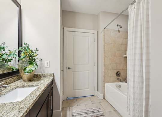 A bathroom with a white door, a white tub, and a white shower curtain.