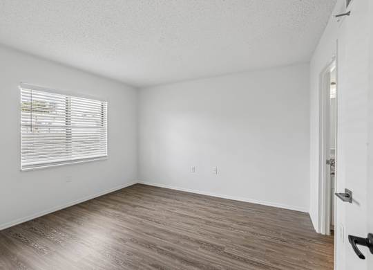 A room with a door and a window with blinds.