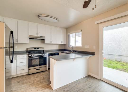 A kitchen with white cabinets and a black fridge.