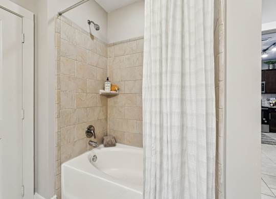 A white bathroom with a tub, shower, and a white door.
