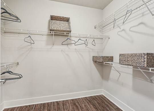 A white closet with a wooden floor and a white door.