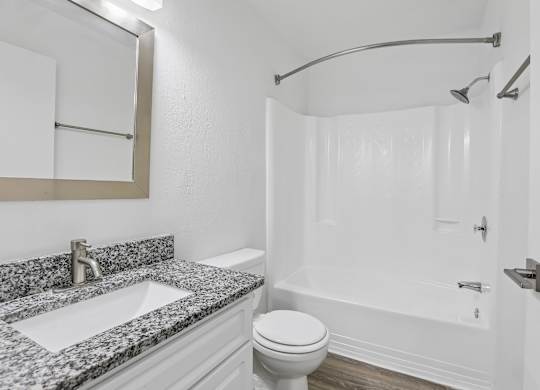 A bathroom with a marble countertop and white fixtures.