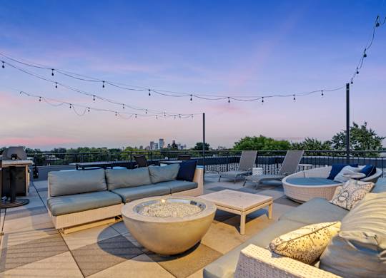a roof deck with couches and chairs and a fire pit