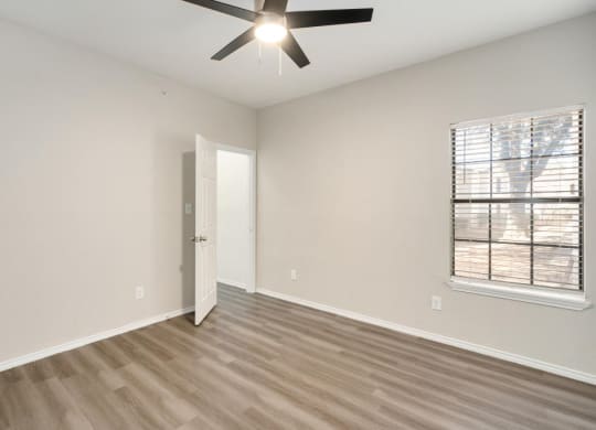 an empty living room with a ceiling fan and a window