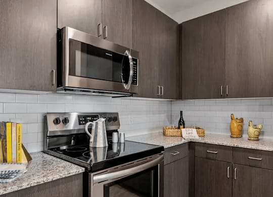 A modern kitchen with dark wood cabinets and stainless steel appliances.