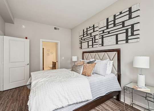 A bedroom with a large bed and a painting on the wall.