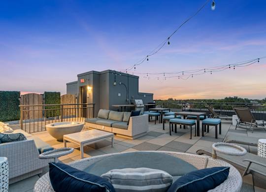 a rooftop patio with couches tables and chairs and a fire pit