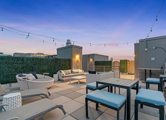 a rooftop patio with tables and chairs and a fire pit