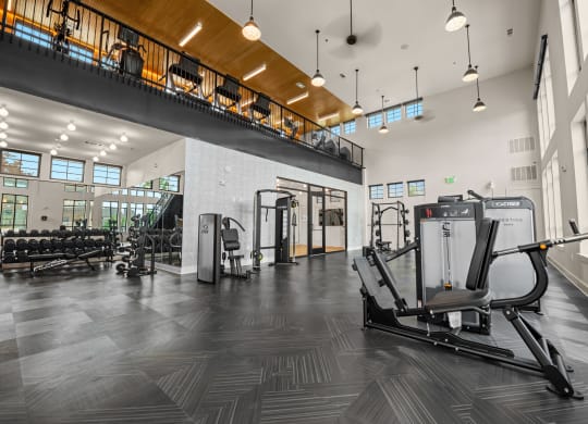 a gym with cardio equipment and weights in a building with tall windows