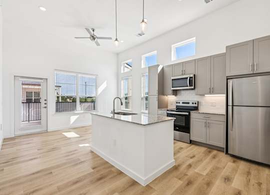 A modern kitchen with stainless steel appliances and wooden floors.