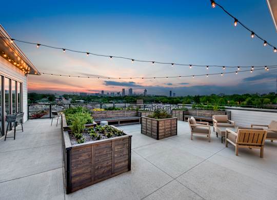 A rooftop patio with wooden furniture and string lights.