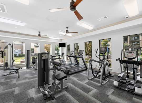A gym with a variety of equipment including a treadmill, weights, and a stationary bike.