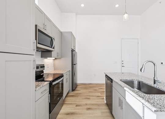 A kitchen with a granite countertop and stainless steel appliances.