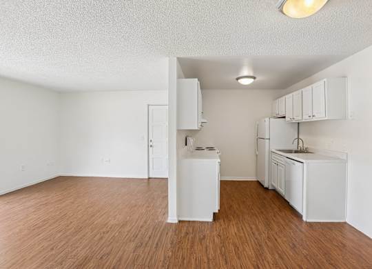 A kitchen with white appliances and wooden floors.