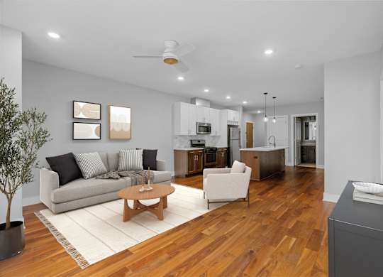 A modern living room with a grey couch, a wooden coffee table, and a flat screen TV mounted on the wall.
